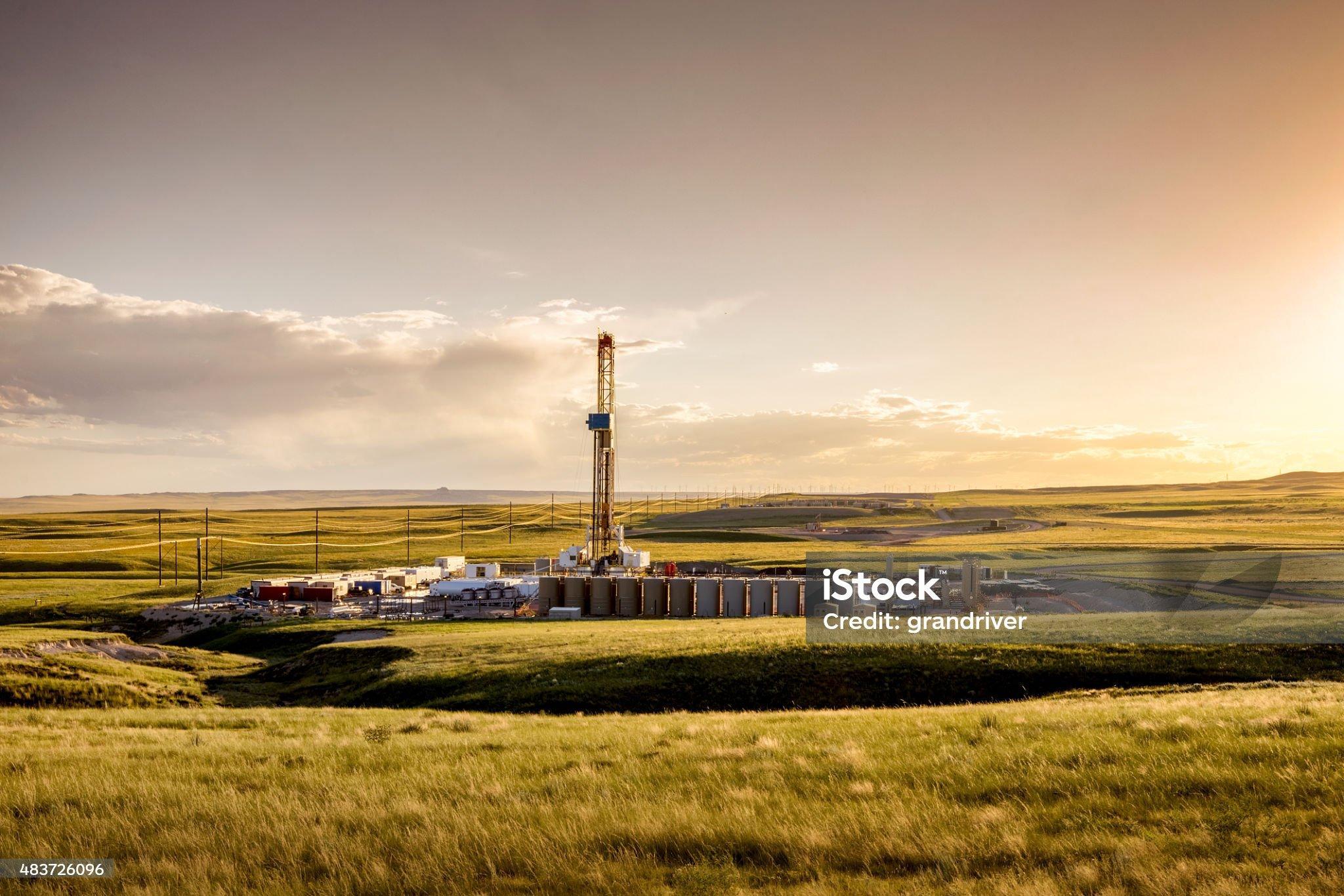 A lone drilling Fracking Rig set against the dramatic landscape of the American Prairie lands.